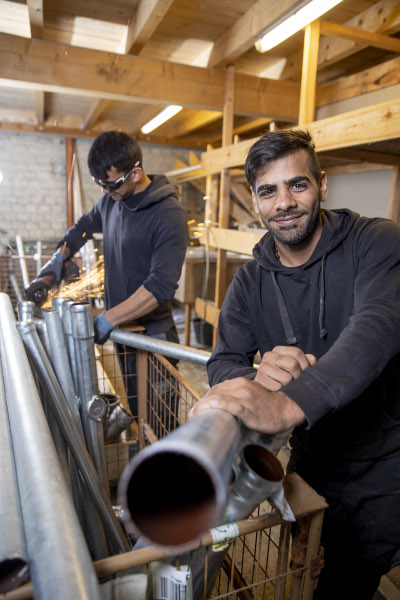 Auszubildender Ramazan Dachdecker lächelt in die Kamera in der Werkstatt